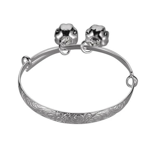 Sterling silver baby scroll bangle with a small bell, designed for infants, featuring intricate scroll detailing and a delicate charm.
